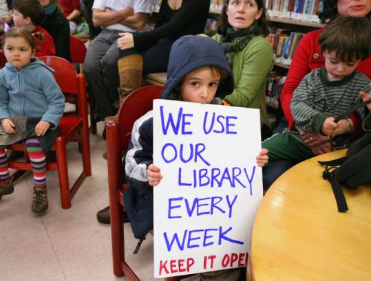 도서관 폐쇄 반대 집회에 참석한 어린이가 ‘우리는 도서관을 매주 사용한다. 도서관 운영을 계속하라’는 피켓을 들고 있다.