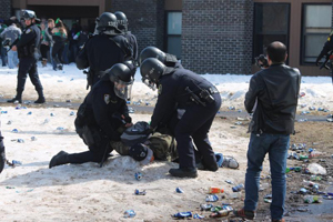 길거리에 술병과 맥주캔이 난무하는 가운데 한 학생이 경찰에게 진압당하고 있다