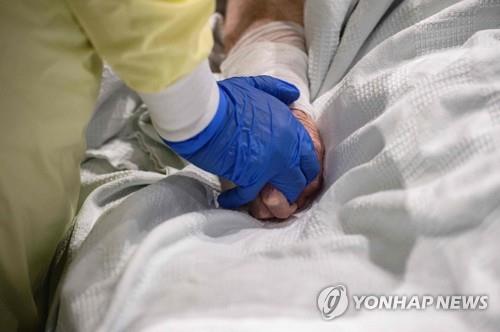 우스터의 UMASS 메모리얼 DCU센터 야전병원에서 의료진이 코로나19 환자의 손을 잡아주고 있다.