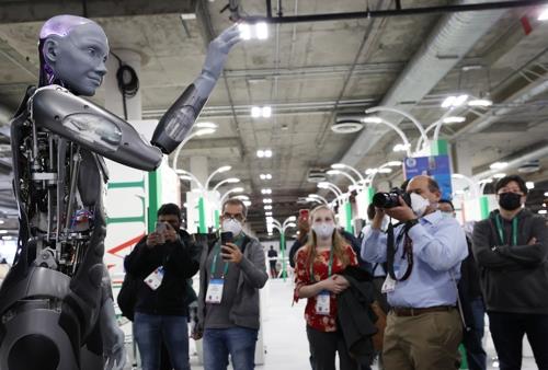 세계 최대 전자·IT 전시회인 CES 2022 이 개막 이틀째인 6일 미국 네바다주 라스베이거스 스타트업 전시공간인 유레카 파크에서 관람객이 영국 로봇기업 '엔지니어드 아트'의 휴머노이드 로봇 '아메카'를 보고 있다. 이 로봇은 관람객의 질문에 적절하게 대답하며 상호작용을 하고 다양한 표정을 지을 수 있다.
